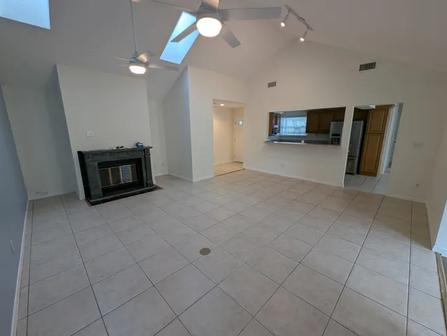 a view of an empty room with kitchen and a window