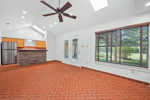a view of an empty room with a window and a kitchen