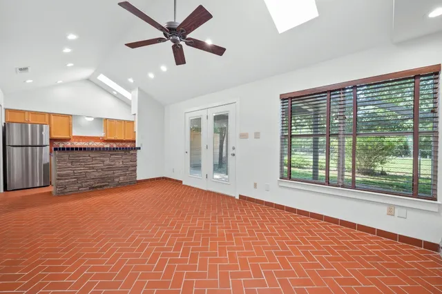 a view of an empty room with a window and a kitchen