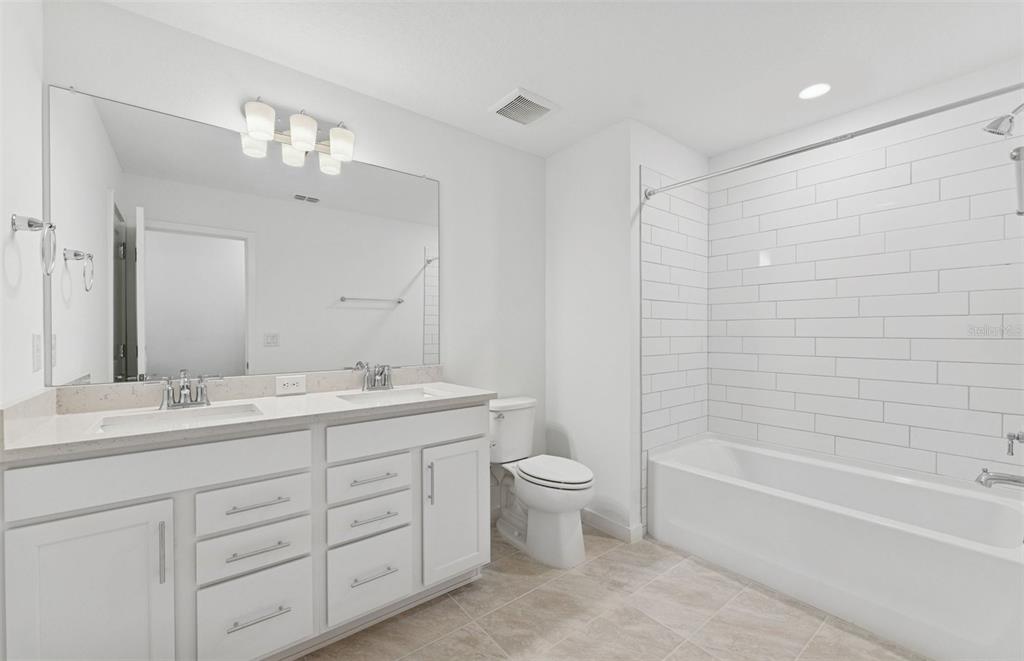 36877 Rio Grande Drive Zephyrhills, FL 33540 - Photo 16 of 26 a bathroom with a double vanity sink a toilet and a bathtub