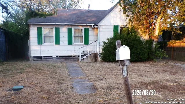 a view of a white house with a yard and a large tree