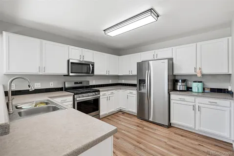a kitchen with granite countertop white cabinets and stainless steel appliances