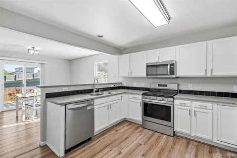a kitchen with white cabinets stainless steel appliances and wooden floor