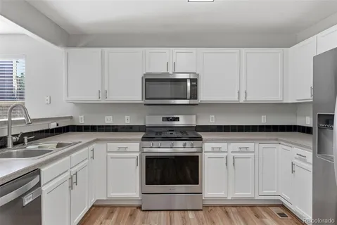 a kitchen with granite countertop white cabinets and stainless steel appliances