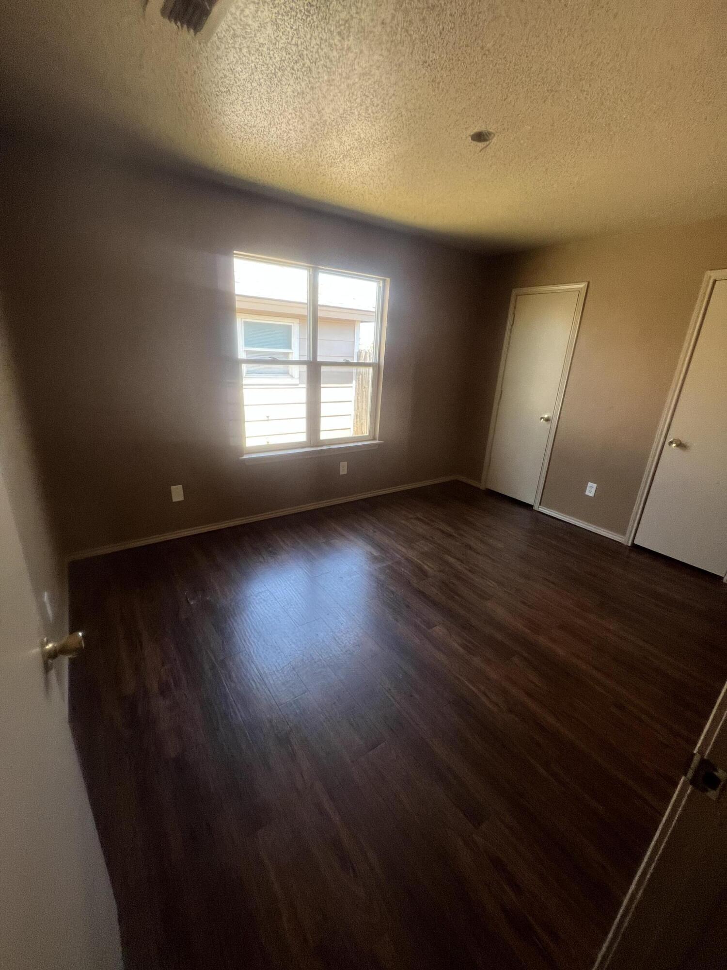 817 Ute Avenue Lubbock, TX 79403 - Photo 11 of 17 an empty room with wooden floor and windows