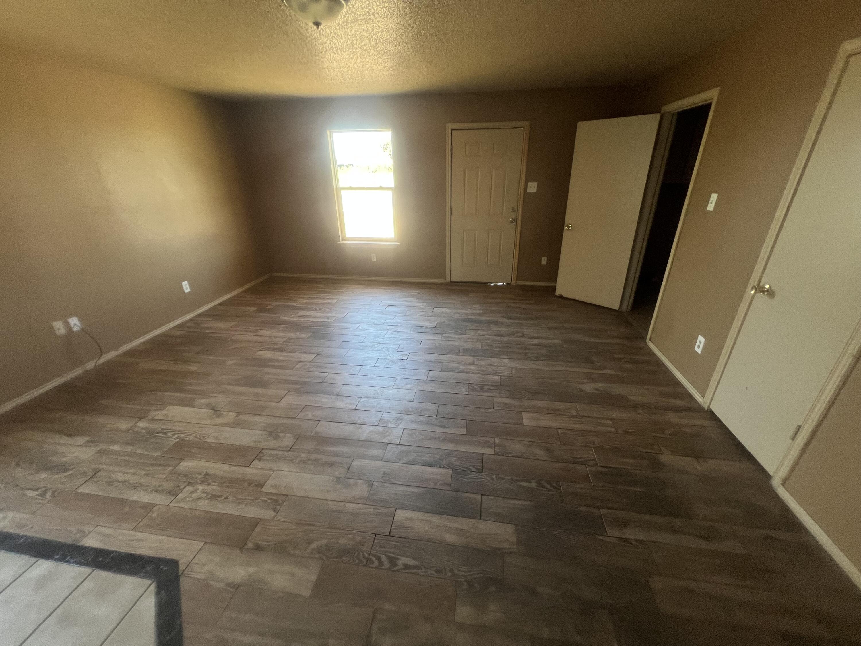 817 Ute Avenue Lubbock, TX 79403 - Photo 6 of 17 an empty room with wooden floor and windows