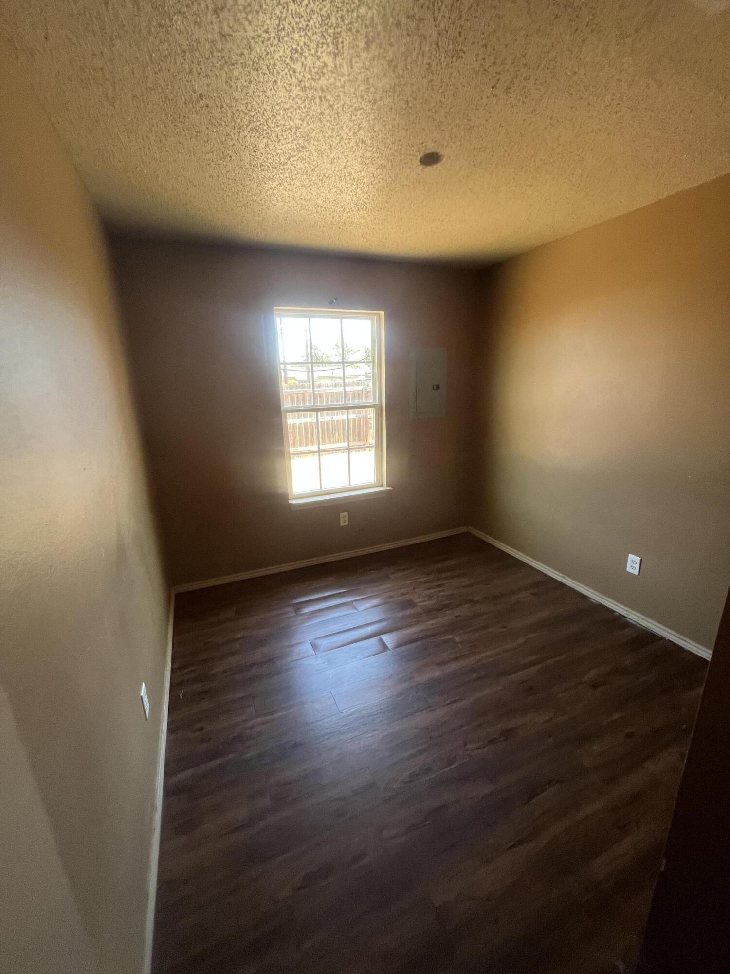 817 Ute Avenue Lubbock, TX 79403 - Photo 9 of 17 an empty room with wooden floor and windows