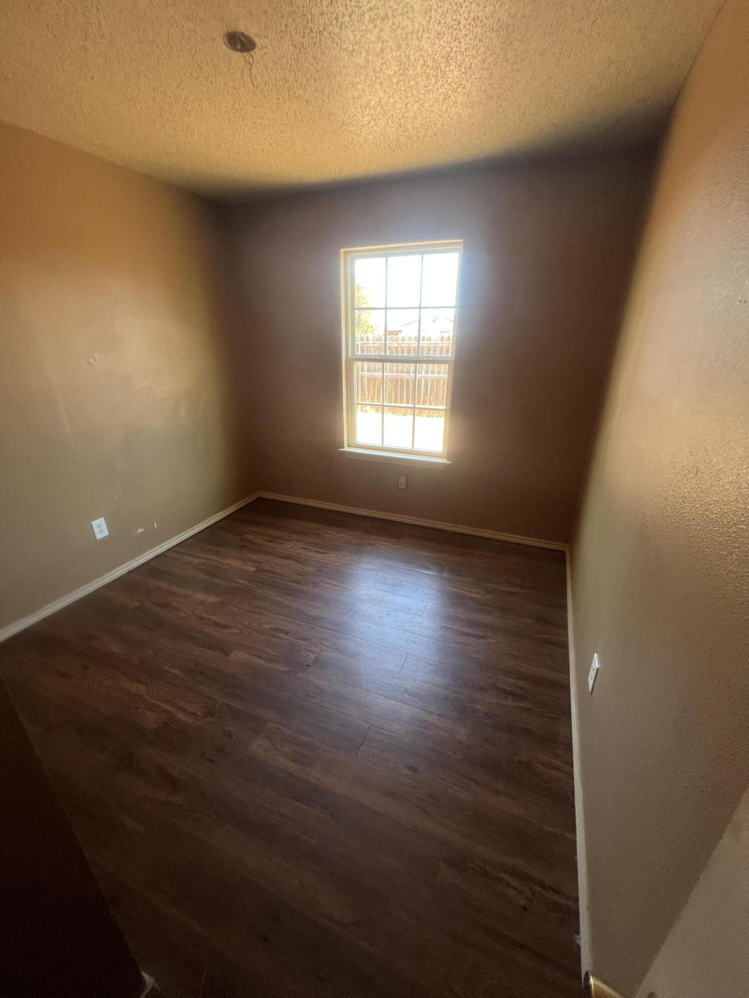 817 Ute Avenue Lubbock, TX 79403 - Photo 10 of 17 an empty room with wooden floor and windows