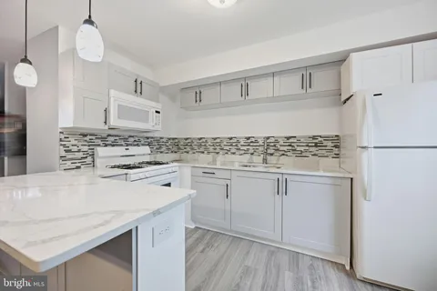 a kitchen with granite countertop white cabinets and white appliances