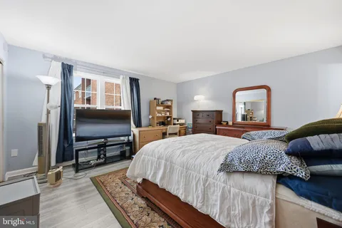 a bedroom with a bed wooden floor and flat screen tv