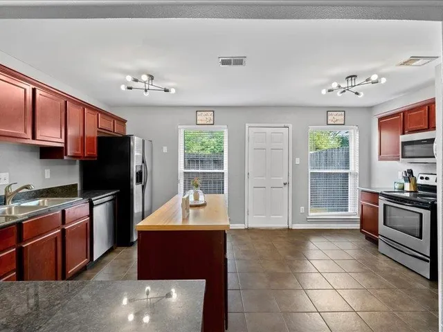 a living room with stainless steel appliances furniture and a flat screen tv