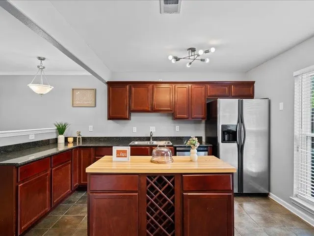 a kitchen with stainless steel appliances granite countertop a stove top oven a sink dishwasher and a refrigerator with wooden cabinets