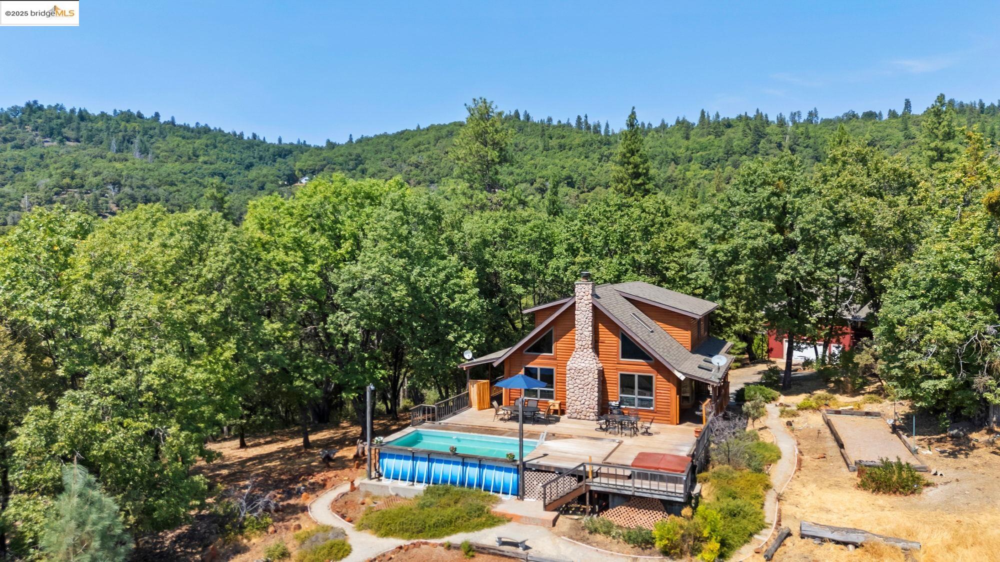 View of swimming pool with a wooden deck and a view of trees