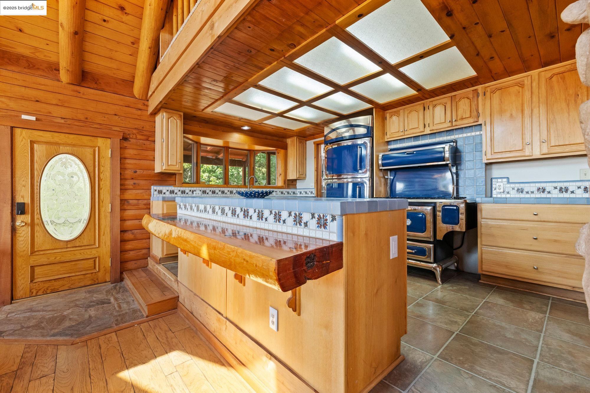 14799 Big Hill Road Sonora, CA 95370 - Photo 13 of 60 Kitchen with wood ceiling, a breakfast bar, decorative backsplash, and tile countertops