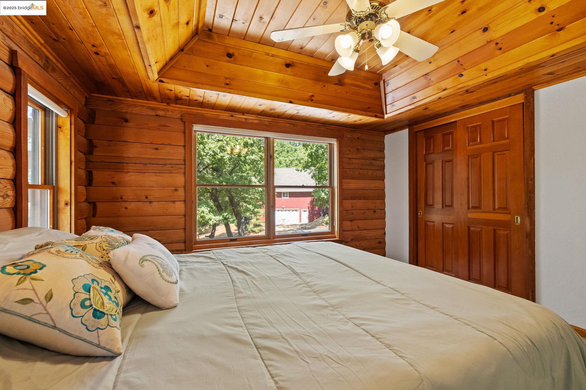 14799 Big Hill Road Sonora, CA 95370 - Photo 23 of 60 Bedroom featuring wood ceiling, log walls, and a ceiling fan