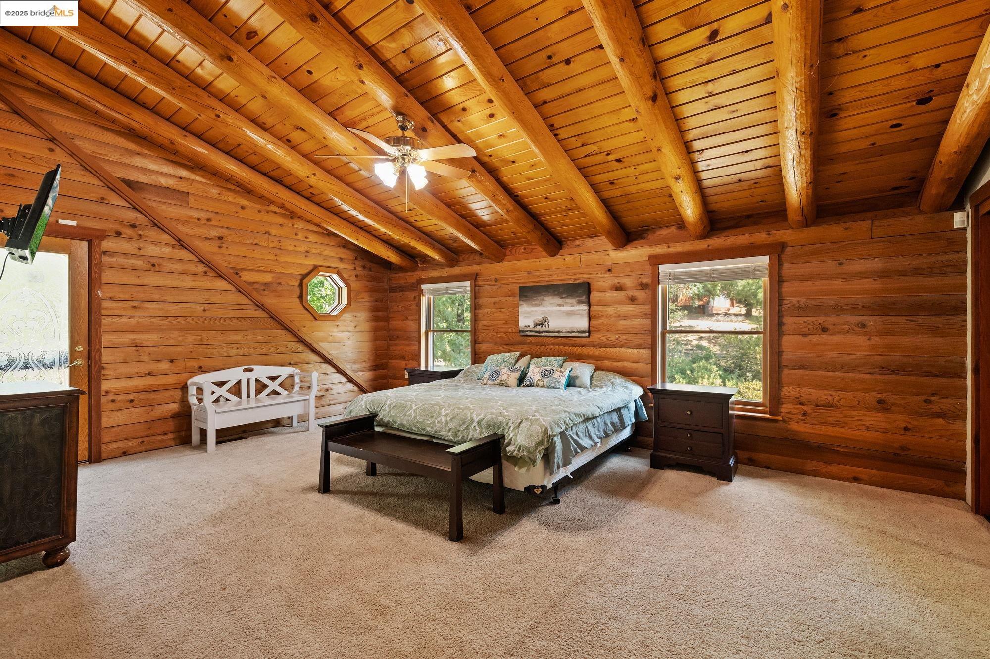 14799 Big Hill Road Sonora, CA 95370 - Photo 27 of 60 Bedroom featuring multiple windows, light carpet, rustic walls, wood ceiling, and wood walls
