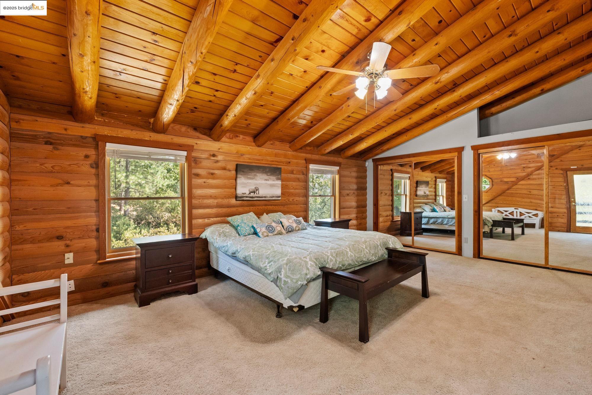 14799 Big Hill Road Sonora, CA 95370 - Photo 28 of 60 Bedroom featuring light carpet, multiple closets, wood ceiling, a ceiling fan, and rustic walls
