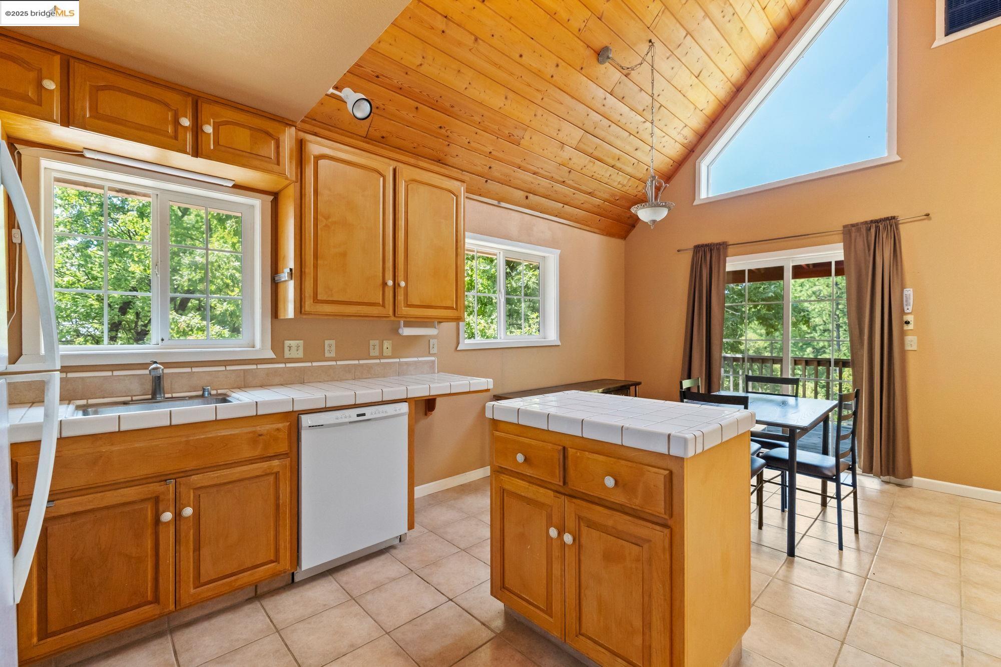 14799 Big Hill Road Sonora, CA 95370 - Photo 38 of 60 Kitchen with wood ceiling, white appliances, light tile patterned flooring, brown cabinetry, and tile counters