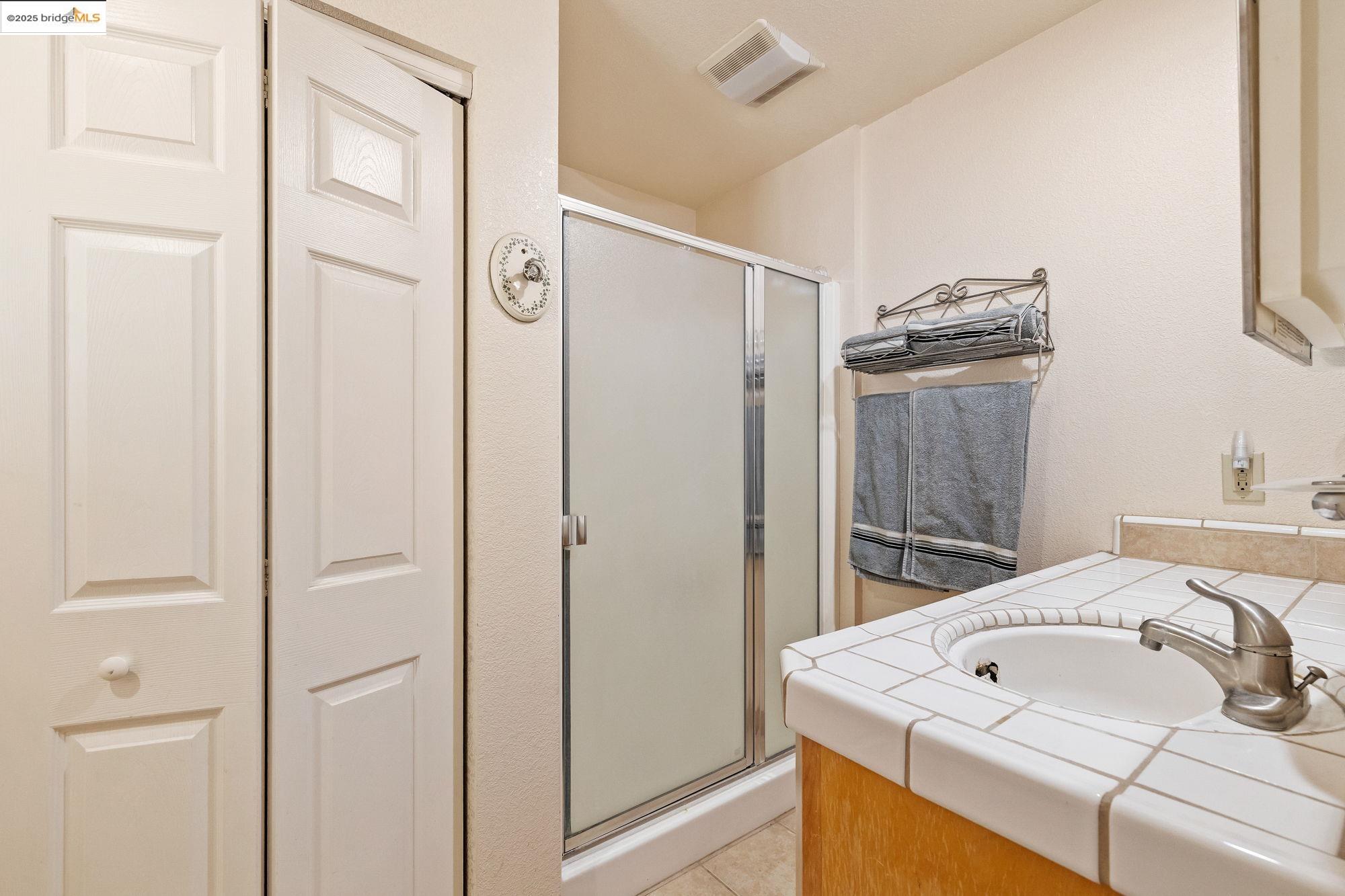 14799 Big Hill Road Sonora, CA 95370 - Photo 41 of 60 Bathroom featuring vanity, a shower stall, light tile patterned floors, and a closet