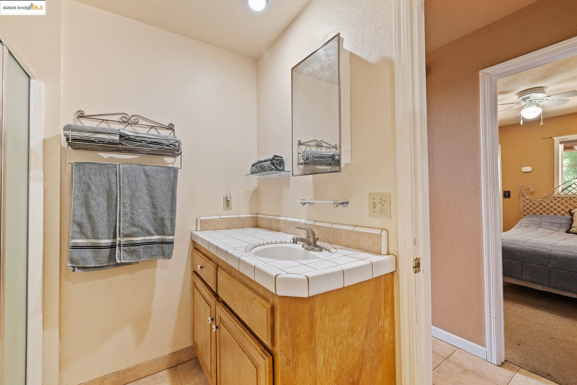 14799 Big Hill Road Sonora, CA 95370 - Photo 42 of 60 Full bath featuring ensuite bathroom, vanity, light tile patterned floors, and ceiling fan