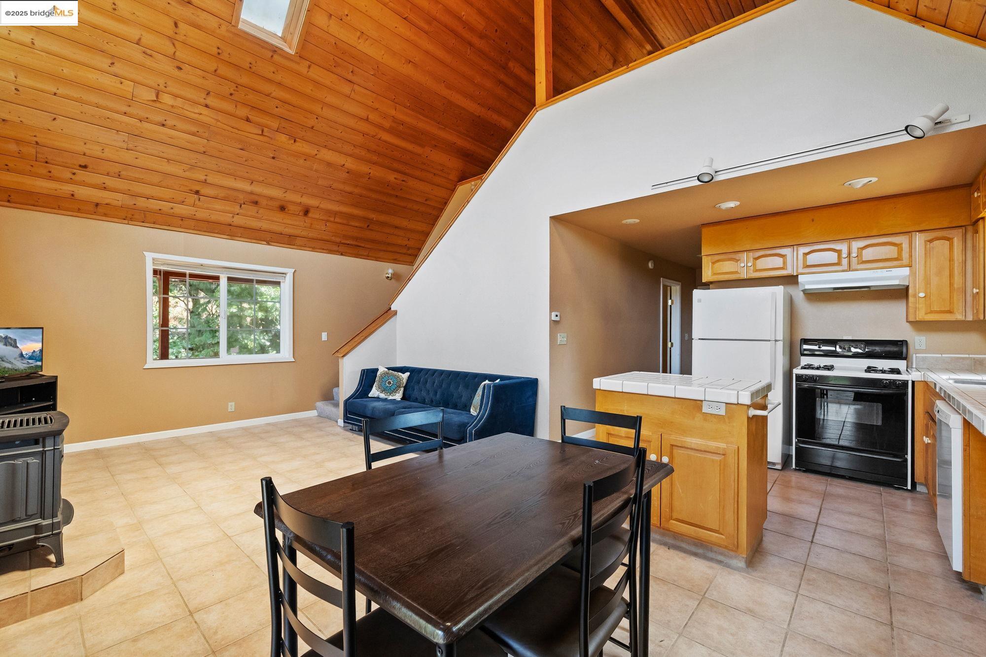 14799 Big Hill Road Sonora, CA 95370 - Photo 45 of 60 Dining area featuring high vaulted ceiling, wood ceiling, stairway, and light tile patterned floors