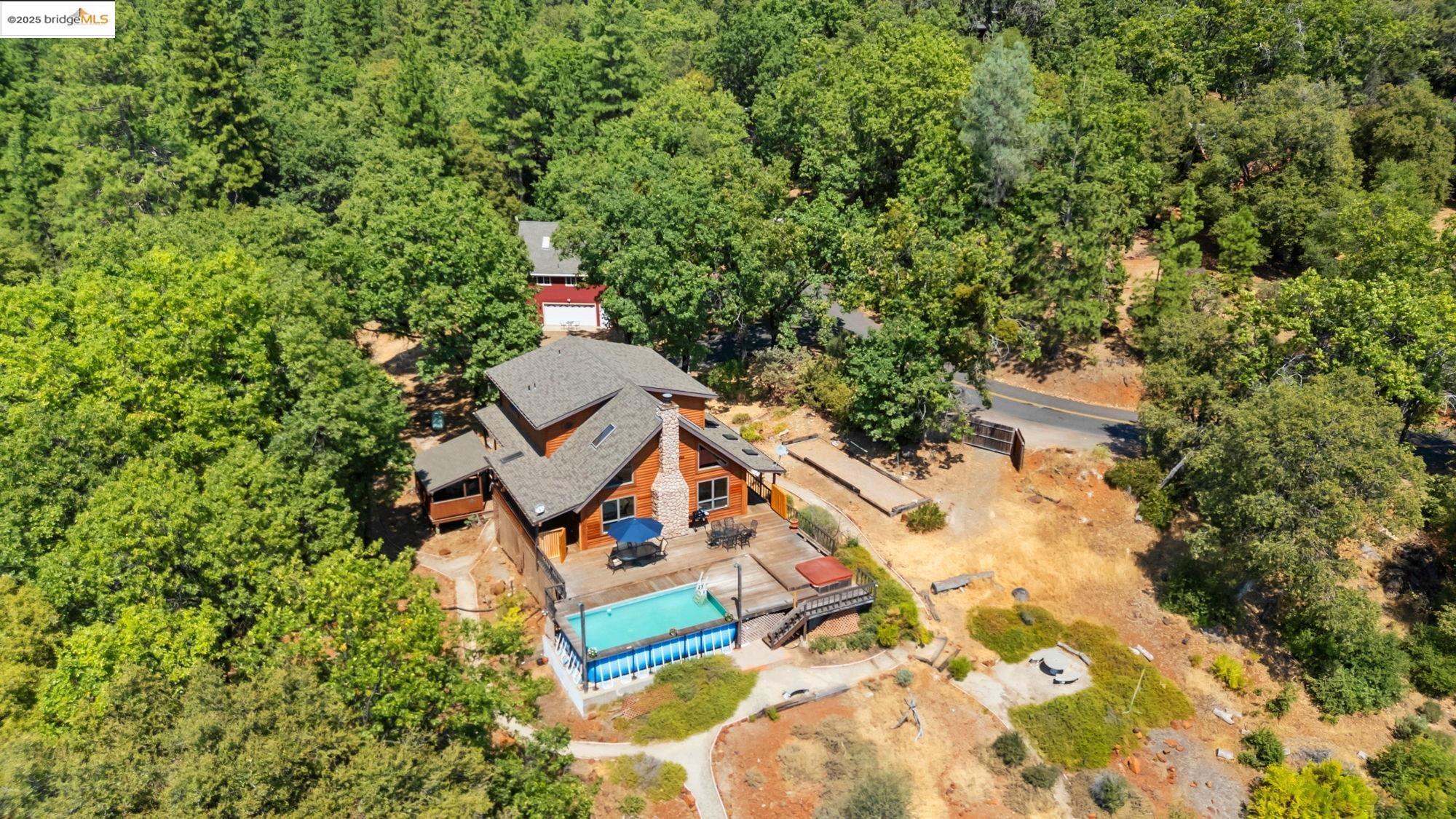 14799 Big Hill Road Sonora, CA 95370 - Photo 60 of 60 Aerial view of property and surrounding area featuring a pool area and a heavily wooded area