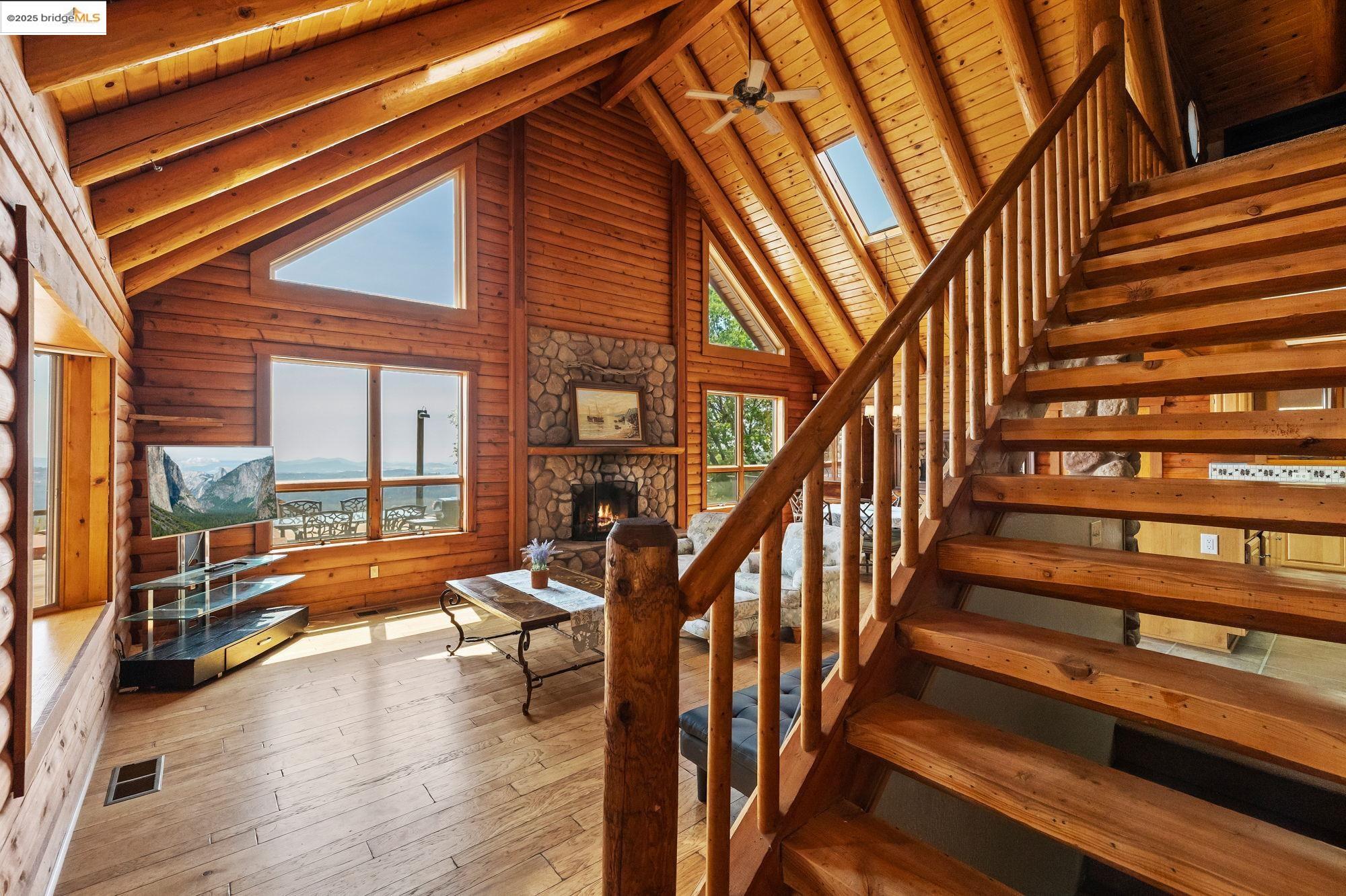 14799 Big Hill Road Sonora, CA 95370 - Photo 6 of 60 Stairs featuring wood-type flooring, a ceiling fan, a wood ceiling with exposed beams, a skylight, and high vaulted ceiling