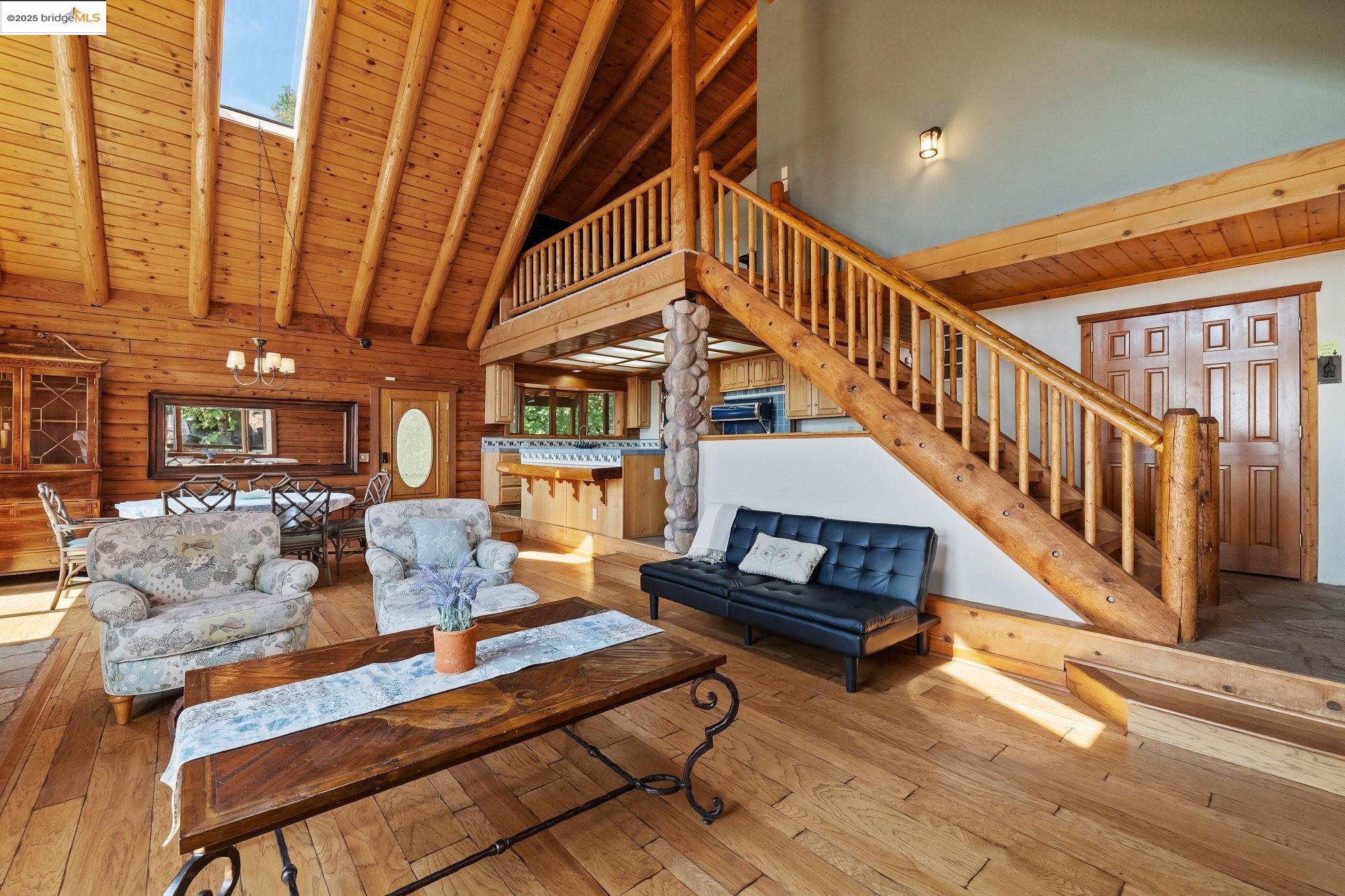 14799 Big Hill Road Sonora, CA 95370 - Photo 8 of 60 Living room with a wood ceiling with exposed beams, hardwood / wood-style flooring, high vaulted ceiling, wood walls, and a skylight