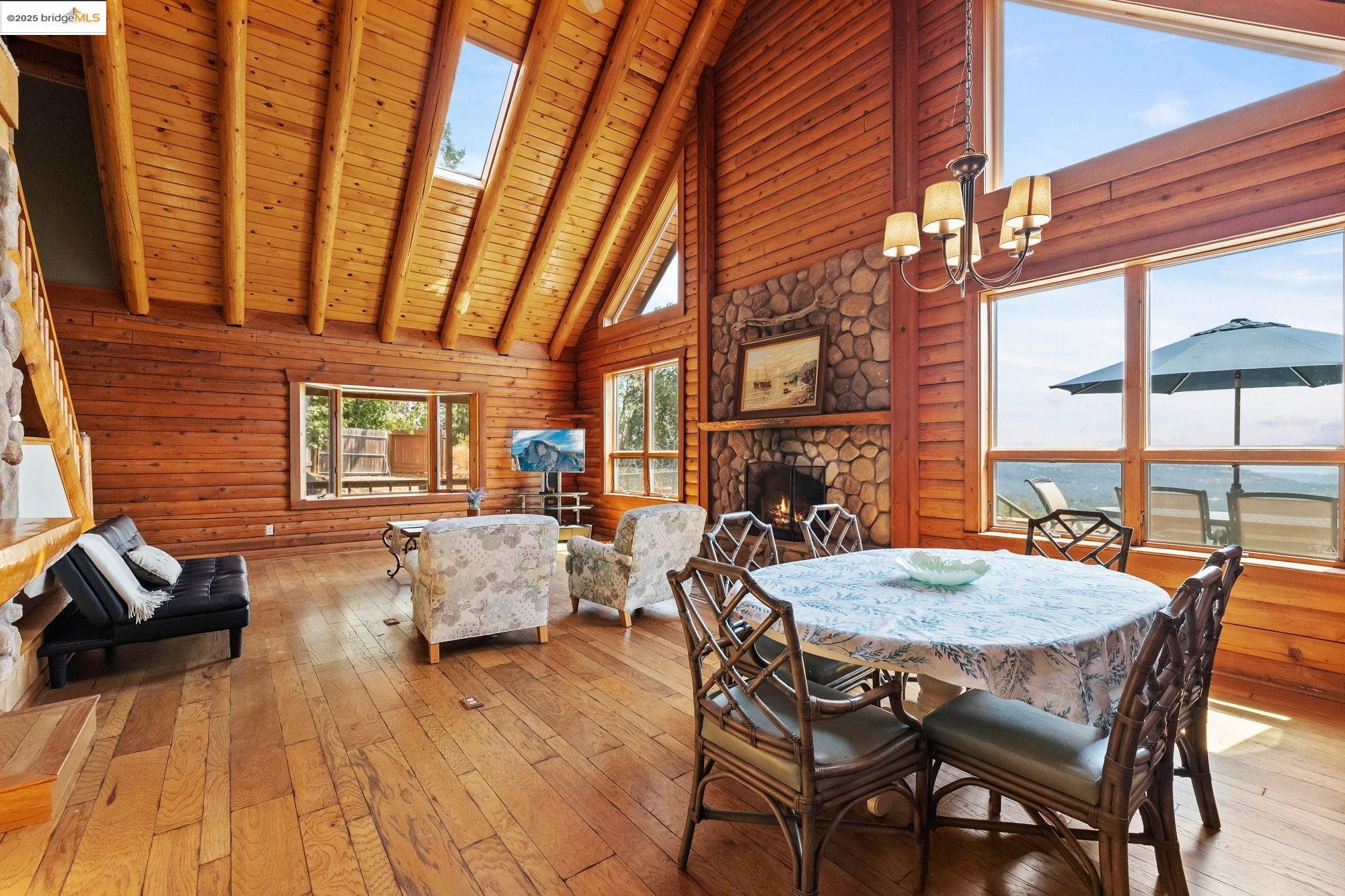 14799 Big Hill Road Sonora, CA 95370 - Photo 10 of 60 Dining area featuring high vaulted ceiling, a fireplace, hardwood / wood-style flooring, a skylight, and a wood ceiling with exposed beams