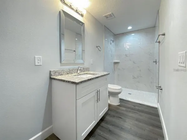 a bathroom with a granite countertop sink a toilet and shower