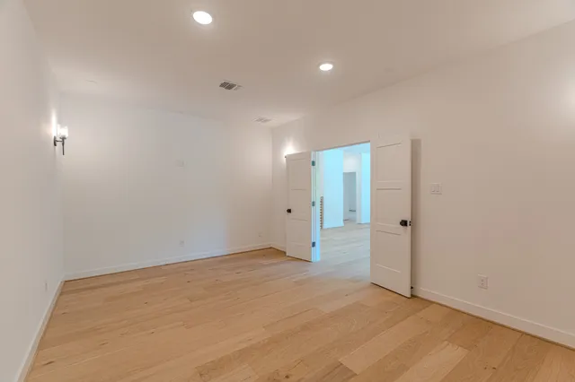 a view of an empty room with wooden floor and a ceiling fan