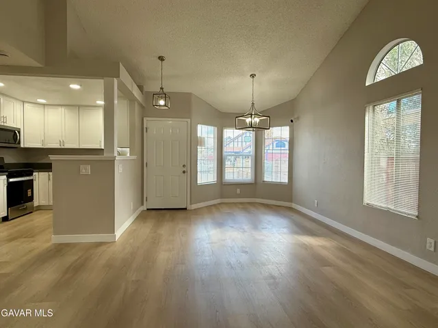 an empty room with wooden floor chandelier and windows