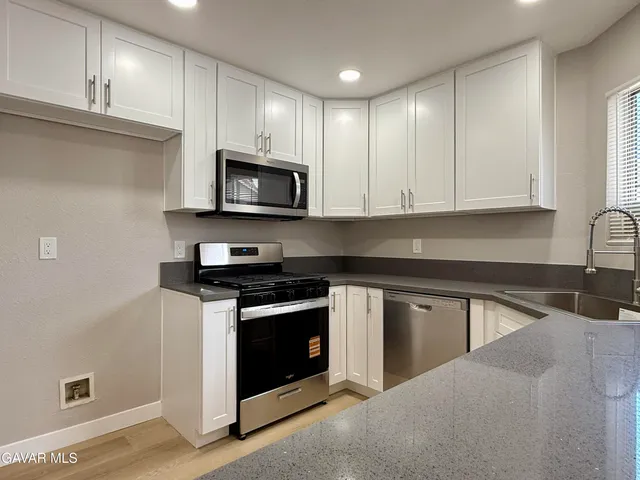 a kitchen with stainless steel appliances granite countertop a stove microwave and sink