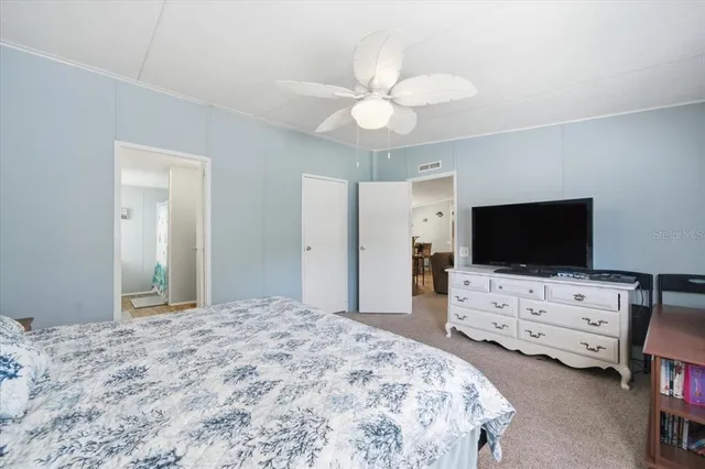 a bedroom with a bed and a flat tv screen on dresser