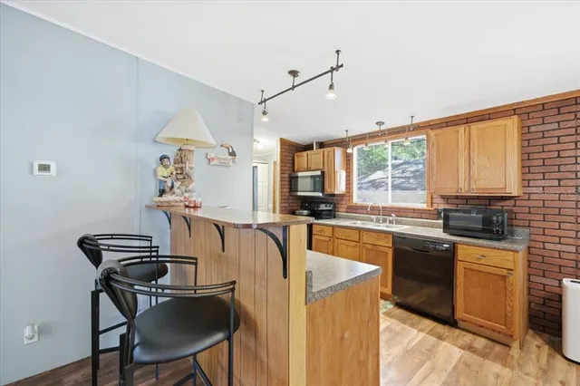 a kitchen with stainless steel appliances kitchen island a table chairs in it and wooden floors