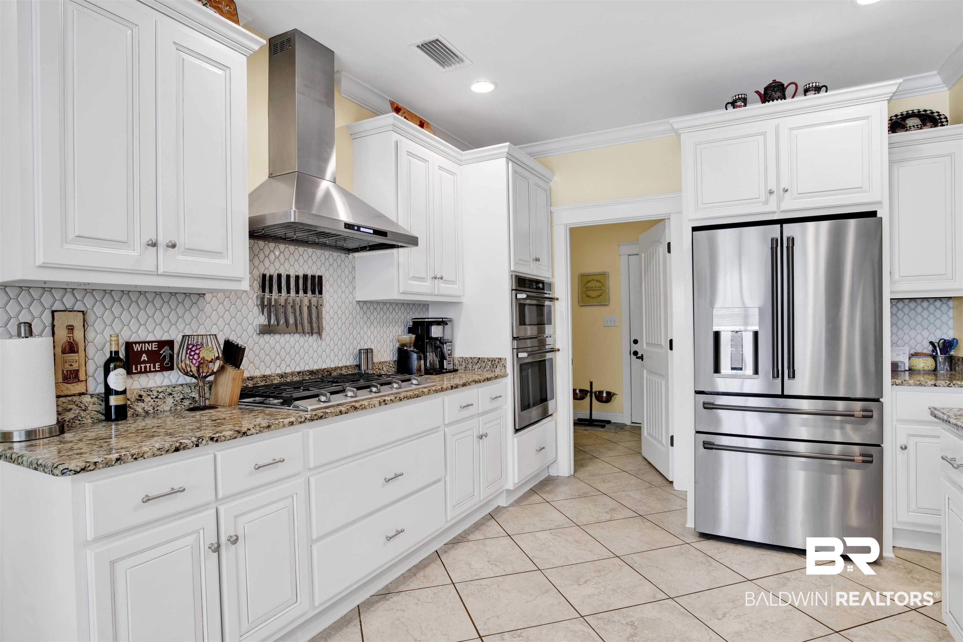 12418 Cambron Trail Daphne, AL 36527 - Photo 24 of 44 Kitchen with wall chimney exhaust hood, light tile patterned floors, backsplash, appliances with stainless steel finishes, and white cabinets