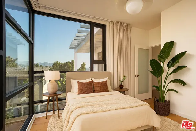 a bedroom with a bed and a large window with outer view