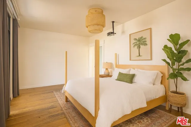 a bedroom with a bed a painting on the wall and a potted plant