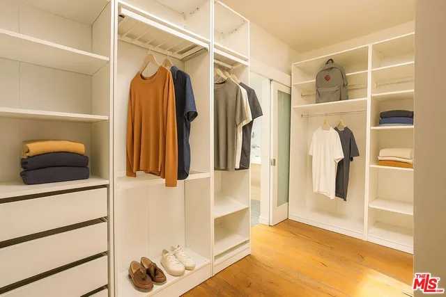 a view of walk in closet with clothes and shoes