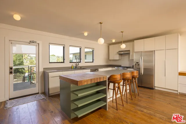 a view of kitchen with stainless steel appliances granite countertop a stove a refrigerator a sink a dining table and chairs with wooden floor