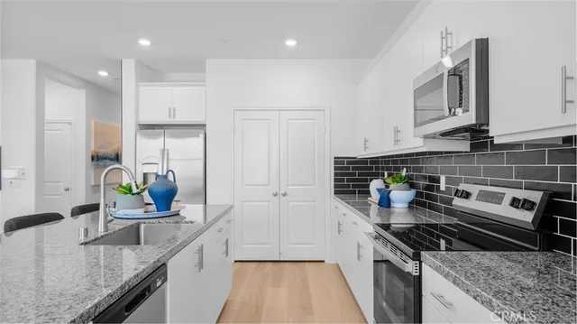 a kitchen with stainless steel appliances granite countertop a sink stove and refrigerator