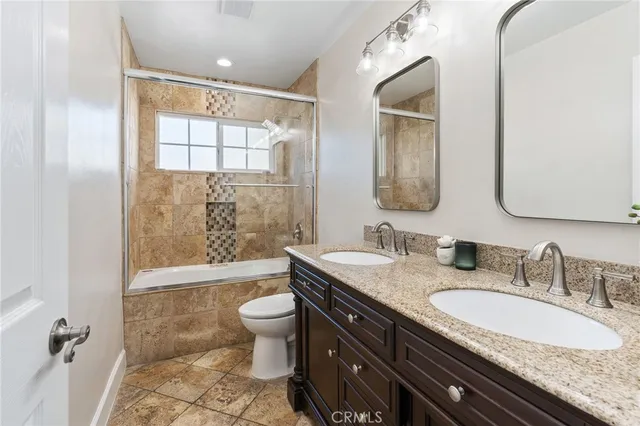 a bathroom with a granite countertop sink a toilet a mirror and shower