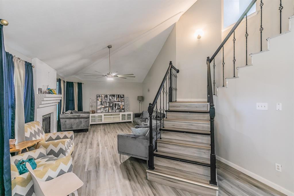 3025 David Drive Rowlett, TX 75088 - Photo 4 of 23 Stairs with a ceiling fan, wood finished floors, a fireplace, and high vaulted ceiling