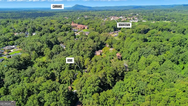 an aerial view of residential house with outdoor space and trees all around