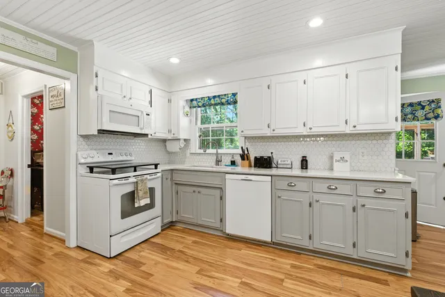 a kitchen with stainless steel appliances granite countertop a stove a sink and white cabinets
