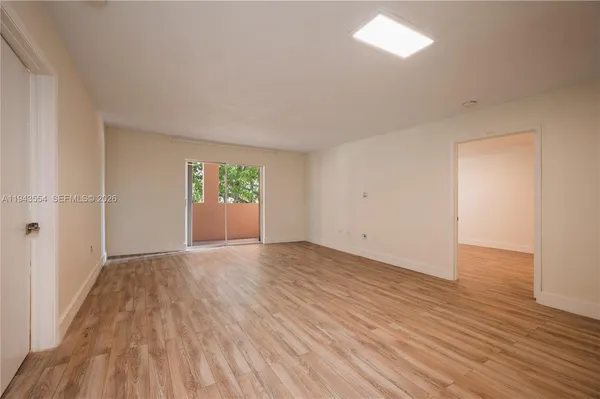 a view of an empty room with wooden floor and a window