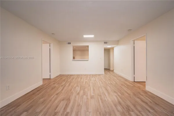 a view of an empty room with wooden floor and a window