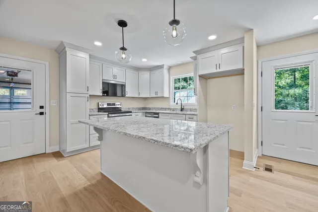 a kitchen with granite countertop white cabinets and stainless steel appliances