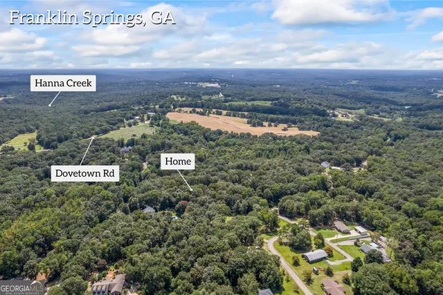 an aerial view of residential house with outdoor space and trees all around