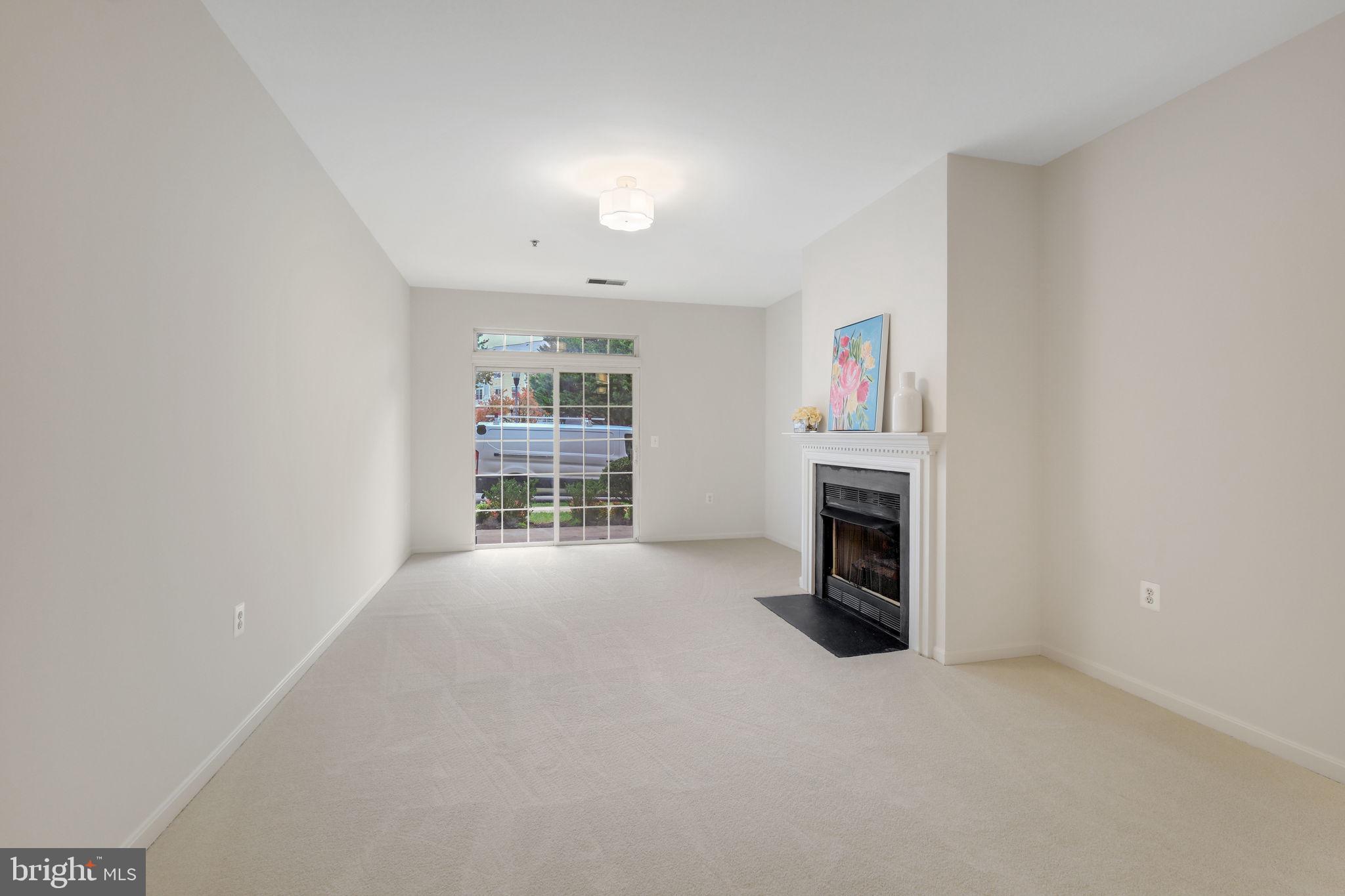 150 Chevy Chase Street, Unit 102 Gaithersburg, MD 20878 - Photo 8 of 41 an empty room with furniture and a fireplace